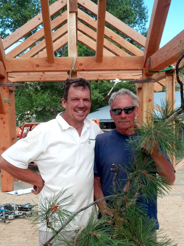 Jonathan and Dave pause for a photo before placing the traditional pine bough at the highest point on the completed frame.