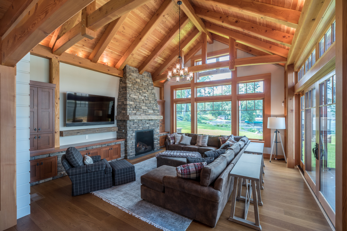 The stone of the fireplace flows down to a lower stone wall (embedded with custom wood cabinets) and continues flowing through the lower level of the home. Photo (c) Scott Hemenway.