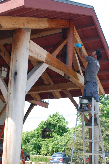 Andy applies a linseed oil finish to a reclaimed timber frame bent over one of the entrances to our Farmington New York office.